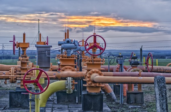 A natural gas field with pipelines and the sun setting in the background.