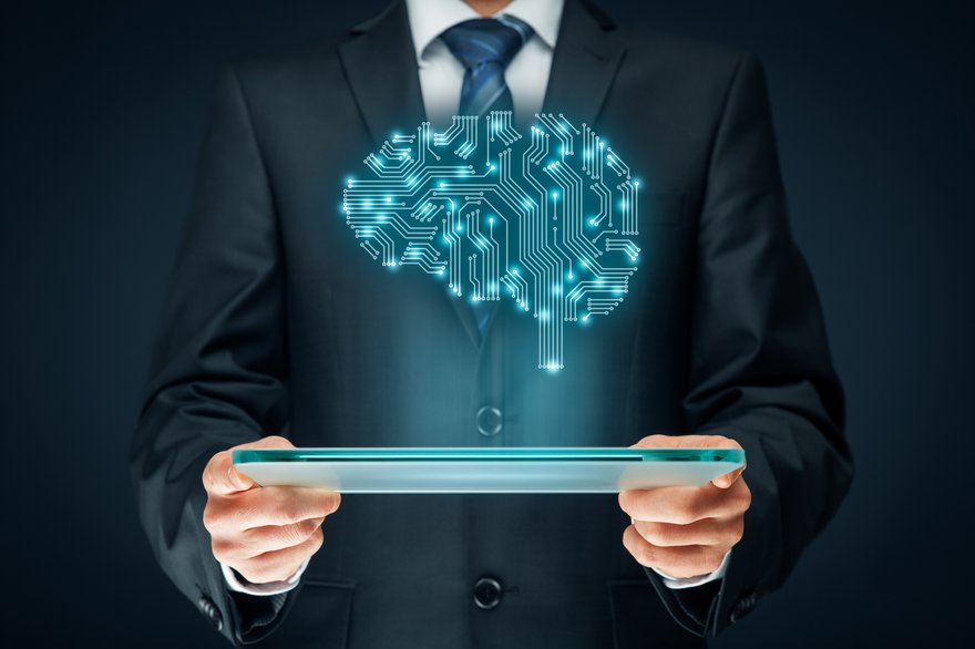 Person in a suit holding a tablet with the image of a brain filled with circuitry projected above it.