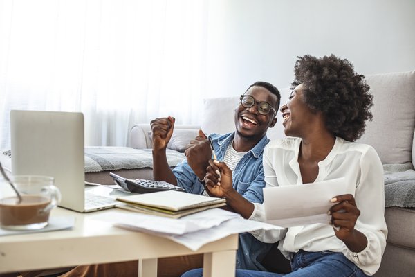 Happy and excited people holding papers and looking at a computer.