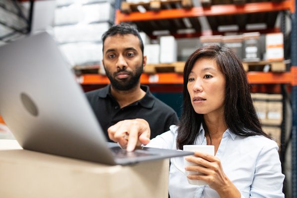 People looking at laptop in a warehouse.