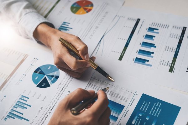 People's hands pointing to data on paperwork.