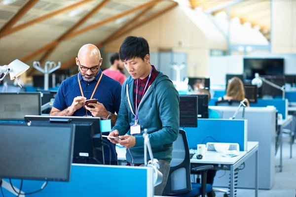 Two men in an office using mobile devices.